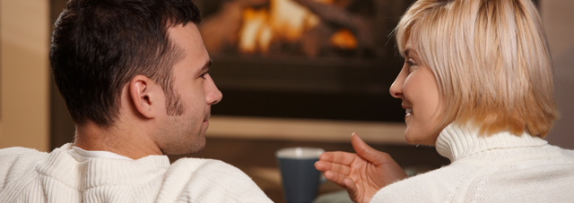 Couple shown chatting by the fire